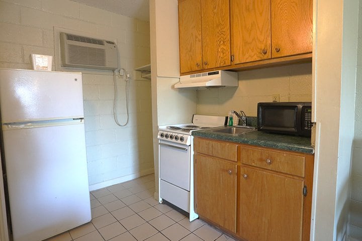 A small kitchenette with a refrigerator, stove, microwave, and sink.