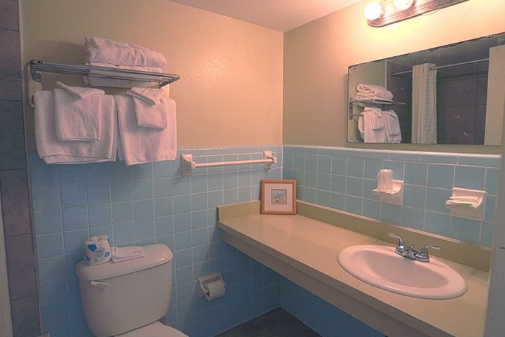 A bathroom with a toilet, sink, and blue tiled walls