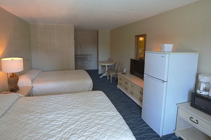 A hotel room with two beds, a refrigerator, and a TV