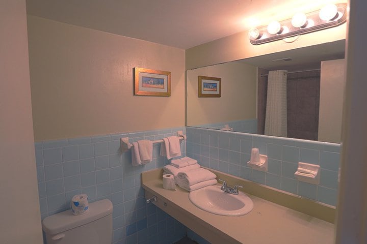 A bathroom with a toilet, sink, and tiled walls.