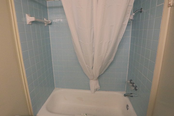 A bathroom with a white bathtub and blue tile walls