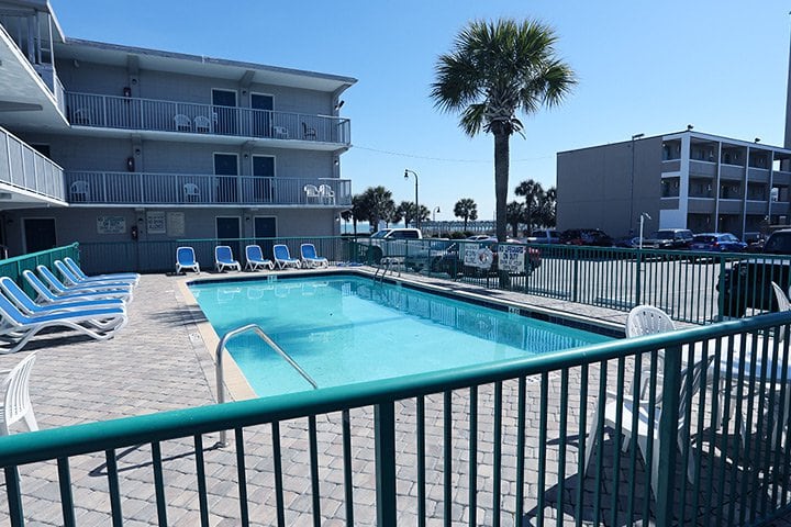 A swimming pool with lounge chairs and a building in the background.